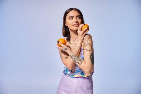 A young woman with brunette hair delicately holds two vibrant oranges in her hands.