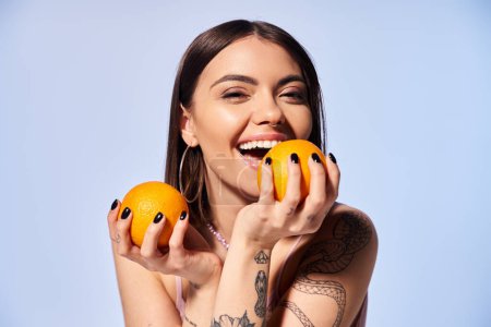 A young woman with brunette hair delicately holds two vibrant oranges in her hands.