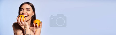 Téléchargez les photos : Une jeune femme aux cheveux bruns tient ludique deux oranges devant son visage dans un décor de studio. - en image libre de droit