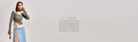 Téléchargez les photos : Une jeune femme élégante aux cheveux bruns portant une jupe en denim, en studio. - en image libre de droit
