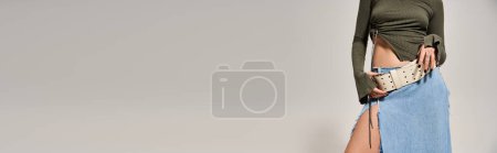 Téléchargez les photos : Brunette femme met en valeur look élégant en haut vert et jupe bleue sur fond de studio. - en image libre de droit