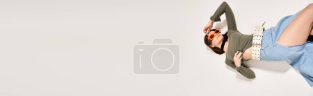 Photo for A young woman with brunette hair is gracefully laying on the ground in a serene studio setting. - Royalty Free Image
