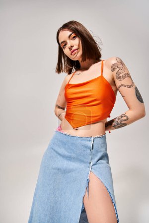 Photo for A young woman with brunette hair dancing gracefully in a vibrant orange top and a flowing blue skirt. - Royalty Free Image