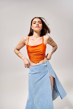 Photo for A brunette woman gracefully poses in a skirt and tank top in a studio setting, radiating elegance and confidence. - Royalty Free Image
