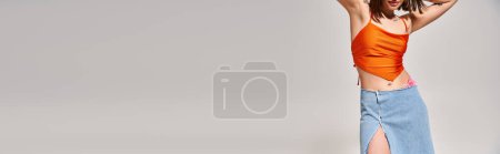 Téléchargez les photos : Une jeune femme brune respire l'élégance dans un haut orange et une jupe bleue dans un décor studio. - en image libre de droit