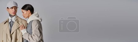 Téléchargez les photos : Un homme et une femme élégamment vêtus de vêtements démodés, debout dans un studio sur un fond gris. - en image libre de droit