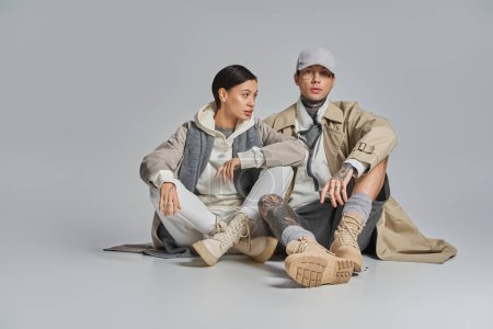 Photo for A man and a woman seated on the ground engaged in deep discussion. The woman, in a stylish trench coat, looks attentive. - Royalty Free Image