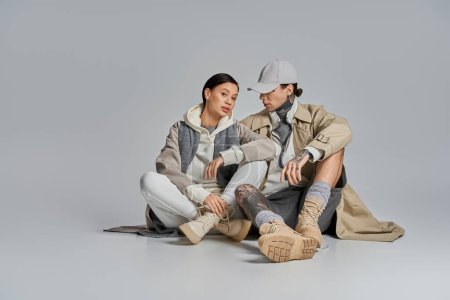 Foto de Un hombre y una mujer con un atuendo elegante se sientan juntos en el suelo, participan en una conversación profunda o momento de conexión. - Imagen libre de derechos