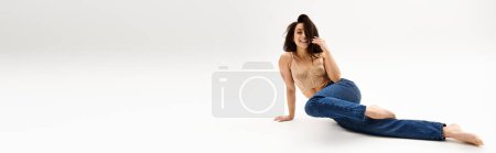 Téléchargez les photos : Une jeune femme respire le charme et la grâce tout en s'asseyant sur le sol avec ses jambes croisées. - en image libre de droit
