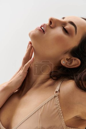Foto de Atractiva joven en lencería toca sensualmente su cuello. - Imagen libre de derechos