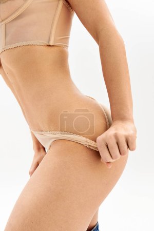 Jeune femme pose de manière provocante en révélant la lingerie.