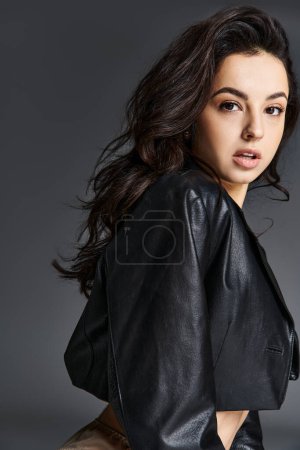 Foto de Una mujer joven con estilo en una chaqueta negra golpea una pose para la cámara. - Imagen libre de derechos
