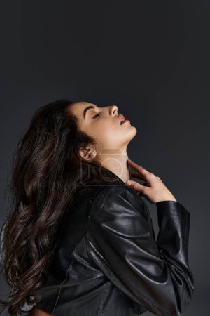 Photo for A captivating young woman with long hair wearing a black leather jacket strikes a pose. - Royalty Free Image