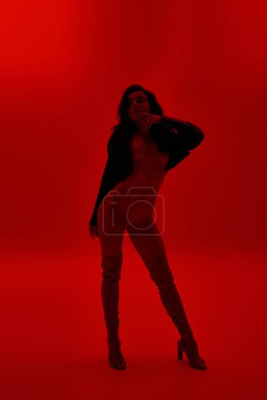 Téléchargez les photos : Une jeune femme pose séduisante sur fond rouge vif. - en image libre de droit