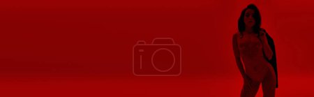Photo for Captivating woman strikes a sensual pose against a vibrant red backdrop. - Royalty Free Image