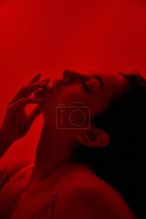 Téléchargez les photos : Une femme en lingerie avec les yeux fermés et la main dans la bouche. - en image libre de droit