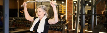 Photo for Attractive mature sportswoman with towel training on lats pulldown machine actively, banner - Royalty Free Image