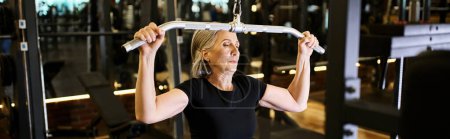 Photo for Beautiful athletic mature sportswoman with towel training on lats pulldown machine actively, banner - Royalty Free Image