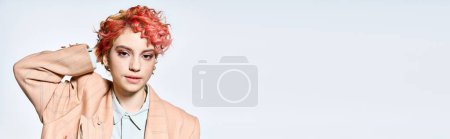 Femme extraordinaire aux cheveux roux se distingue dans une veste rose.