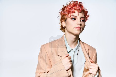 Foto de Una mujer llamativa con el pelo rojo vibrante se levanta alto, exudando confianza en una chaqueta con estilo. - Imagen libre de derechos