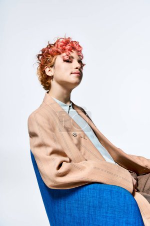 Téléchargez les photos : Une femme aux cheveux roux assise sur une chaise bleue. - en image libre de droit