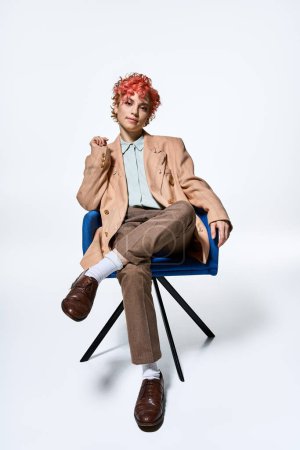 Extraordinary woman with red hair sits comfortably on a blue chair.
