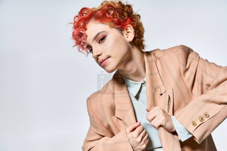 Eine dynamische Frau mit roten Haaren posiert selbstbewusst.