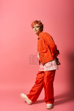 Extraordinary woman dressed in an orange jacket and red pants stands out against a vibrant background.