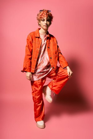 Photo for An extravagant woman stands out in an orange jacket and red pants. - Royalty Free Image