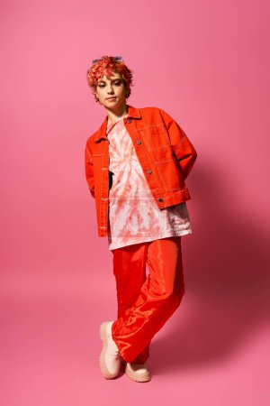 Foto de Mujer joven se destaca en colorido atuendo de chaqueta naranja y pantalones rojos. - Imagen libre de derechos
