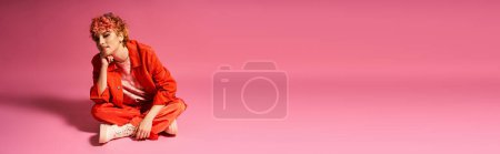 Foto de Mujer extraordinaria sentada con gracia en la superficie rosa con fondo a juego. - Imagen libre de derechos