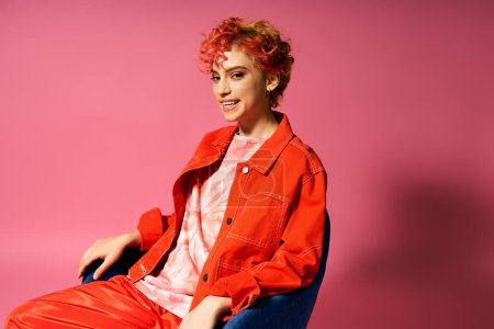 Téléchargez les photos : Une femme vibrante aux cheveux roux assise gracieusement sur une chaise bleue. - en image libre de droit