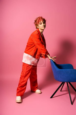 Mujer extraordinaria en un traje rojo empujando una silla azul vibrante.