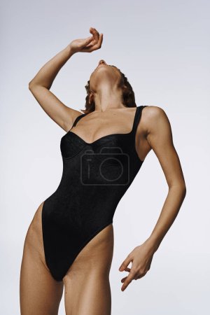 Foto de Una joven mujer exuda elegancia en un traje de baño negro de una sola pieza. - Imagen libre de derechos