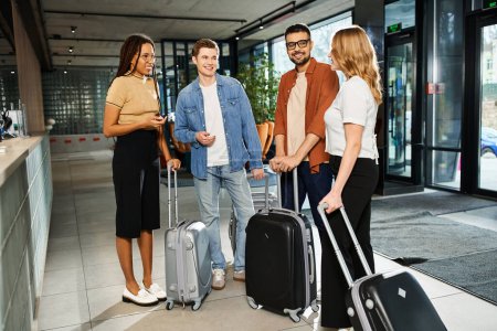 Téléchargez les photos : Collèges multiculturels en tenue décontractée debout avec des bagages dans un hall d'hôtel lors d'un voyage d'affaires. - en image libre de droit