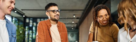 Photo for Multicultural colleagues in casual attire standing around each other in a hotel lobby during a corporate trip. - Royalty Free Image