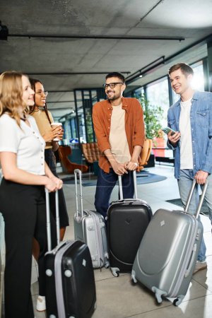 Colegas multiculturales en atuendo casual reunidos en un vestíbulo de hotel con equipaje, preparándose para un viaje corporativo.