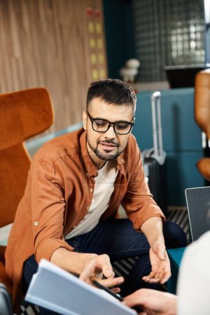 Photo for A man in glasses sits on the couch, engrossed in laptop. - Royalty Free Image
