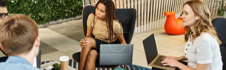 Téléchargez les photos : Une femme concentrée sur son ordinateur portable alors qu'elle était assise sur une chaise, incarnant le style de vie moderne d'une équipe de start-up. - en image libre de droit