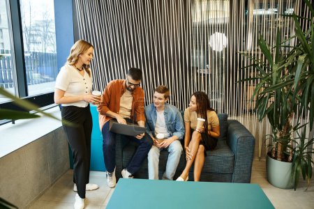 A group of colleagues from a startup team work together around a stylish blue couch in a modern business setting.