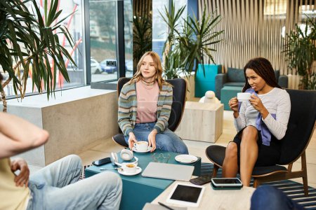 Foto de Un grupo de personas colaborando e ideando ideas mientras se sientan alrededor de una elegante mesa de café en un moderno espacio de coworking. - Imagen libre de derechos