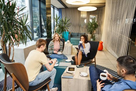 A diverse group of colleagues in a coworking space engages in discussions and collaboration in a contemporary living room setting.