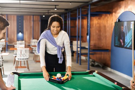 A woman and a man, colleagues in a coworking space, enjoy a game of pool, showcasing a modern business lifestyle.