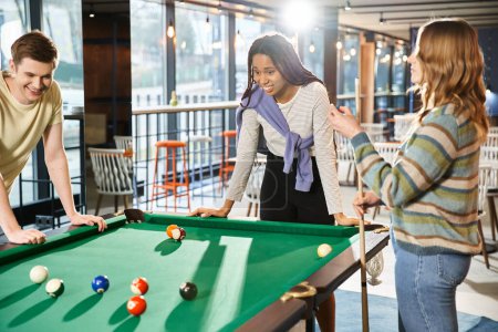 Photo for Colleagues from a coworking space challenge their startup team members to a game of pool during a break. - Royalty Free Image