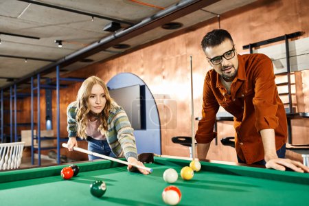 Un hombre y una mujer participan en un juego de billar, mostrando el trabajo en equipo y la camaradería en un entorno empresarial moderno.