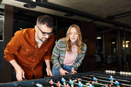 Foto de Un hombre y una mujer participan enérgicamente en un juego, mostrando el trabajo en equipo y la camaradería en un espacio de coworking moderno. - Imagen libre de derechos