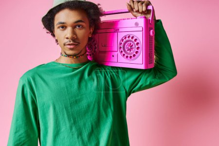 African American man with curly hair holds a pink radio to his face against a pink background.