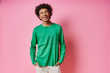 Photo for A cheerful young African American man in casual wear stands in front of a pink wall, showcasing his emotions. - Royalty Free Image
