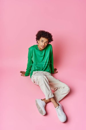 Photo for A young African American man with curly hair relaxes on a pink background. - Royalty Free Image