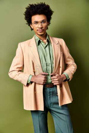 Foto de Elegante joven afroamericano con traje y gafas posando con confianza sobre un fondo verde vibrante. - Imagen libre de derechos